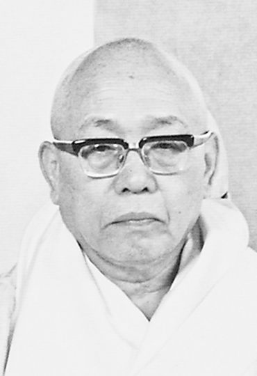 法衣をまとい、眼鏡をかけた年配男性の白黒肖像写真
